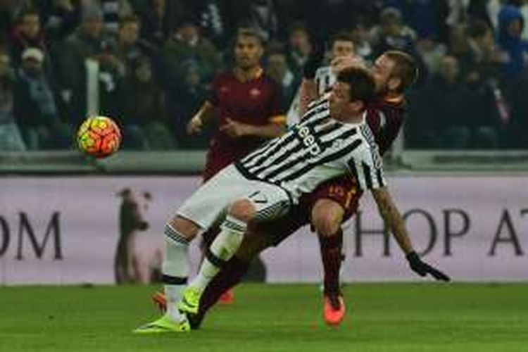 Striker Juventus, Mario Mandzukic, berebut bola dengan gelandang AS Roma, Daniele De Rossi, saat kedua tim bertanding pada lanjutan Serie A di Juventus Stadium, Minggu (24/1/2016).