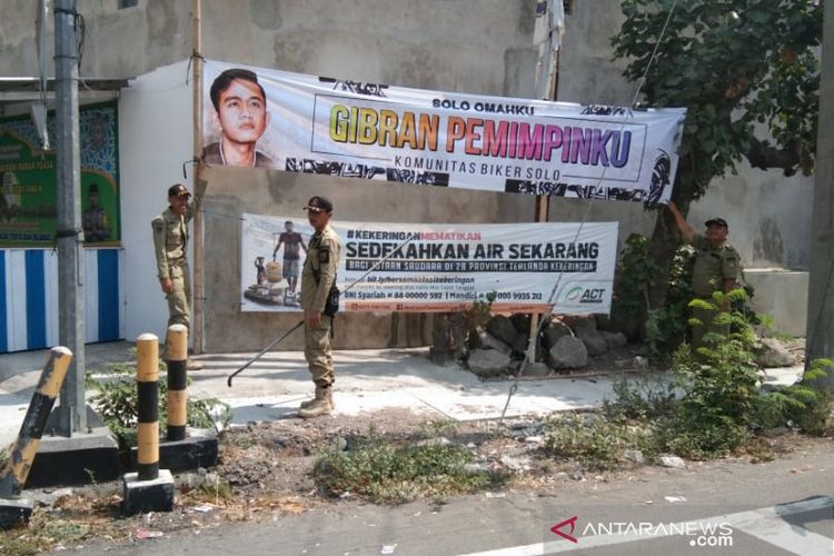 Sejumlah petugas Satpol PP Surakarta menertibkan spanduk bergambar Gibran Rakabuming Raka. 