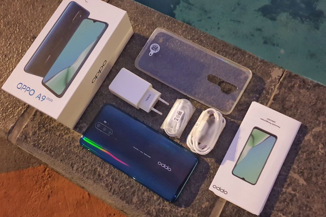 Oppo A9 2020 bersama dengan isi kotak penjualan. Ketika membeli Oppo A9 2020, pengguna akan mendapatkan travel adapter, earphone, soft case bawaan, beserta kabel data USB Type-C. (KOMPAS.com/Bill Clinten)
