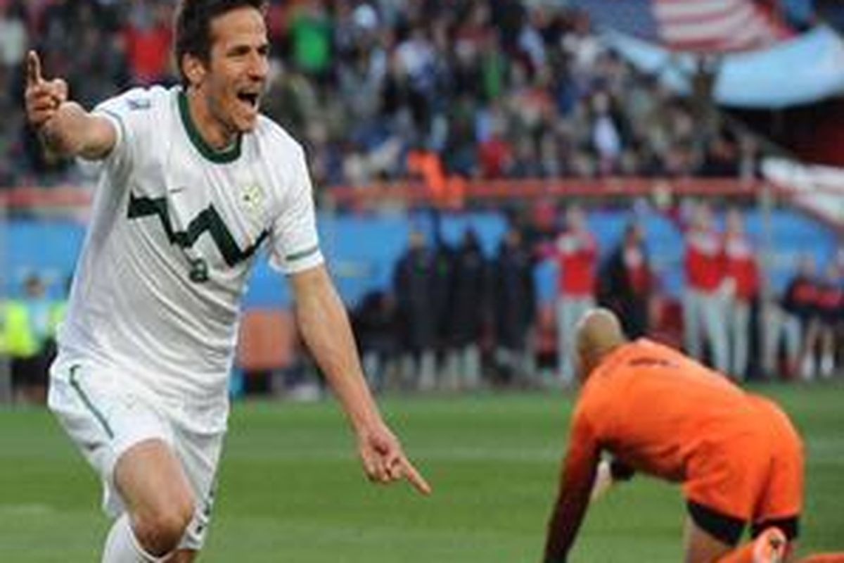 Pemain Slovenia, Zlatan Ljubijankic, merayakan gol yang dicetaknya, sedangkan kiper AS, Tim Howard, hanya terduduk lesu.