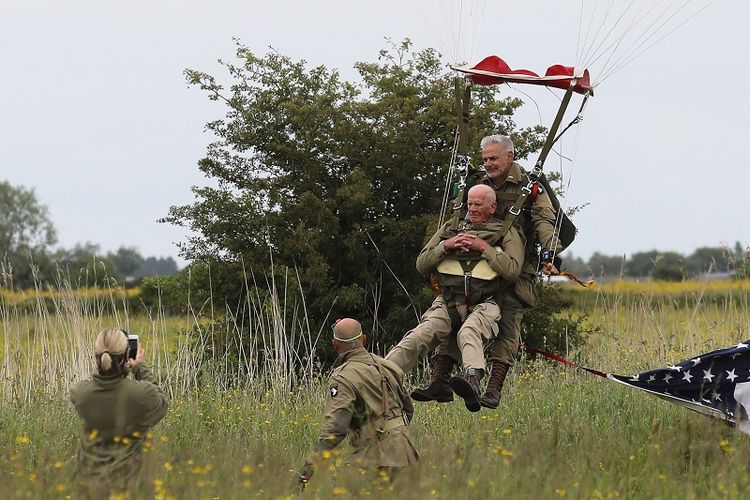 Veteran Perang Dunia II asal AS Tom Rice (depan) mendarat ketika ambil bagian dalam aksi terjun payung di Carentan, Normandia, Perancis, Rabu (5/6/2019). (LUDOVIC MARIN/AFP)