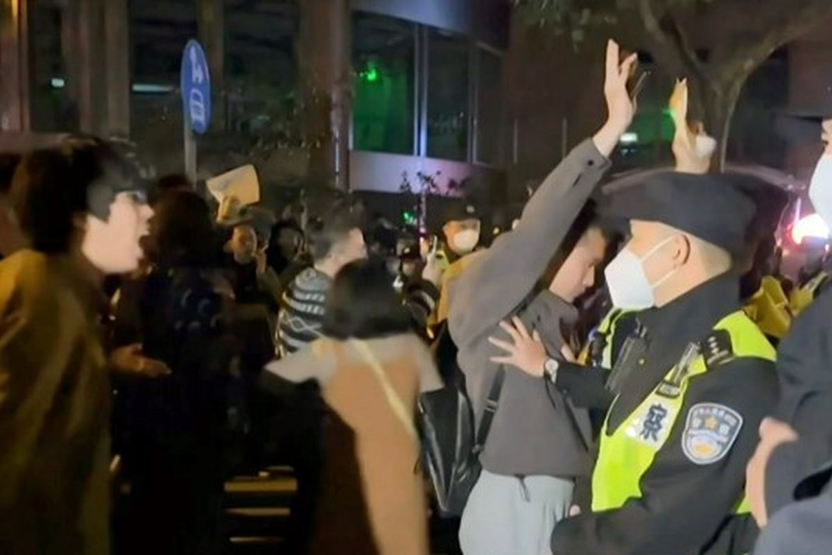 Cuplikan bingkai dari rekaman video saksi mata yang tersedia melalui AFPTV pada 27 November 2022 menunjukkan para demonstran meneriakkan slogan-slogan saat polisi mempertahankan posisi mereka, di Shanghai.  Kerumunan yang marah turun ke jalan di Shanghai pada dini hari tanggal 27 November dan video di media sosial menunjukkan protes di kota-kota lain di seluruh China, ketika penentangan publik terhadap kebijakan nol-Covid garis keras pemerintah meningkat. Sementara itu, wartawan BBC dilaporkan sempat ditahan dan dipukuli polisi saat meliput protes