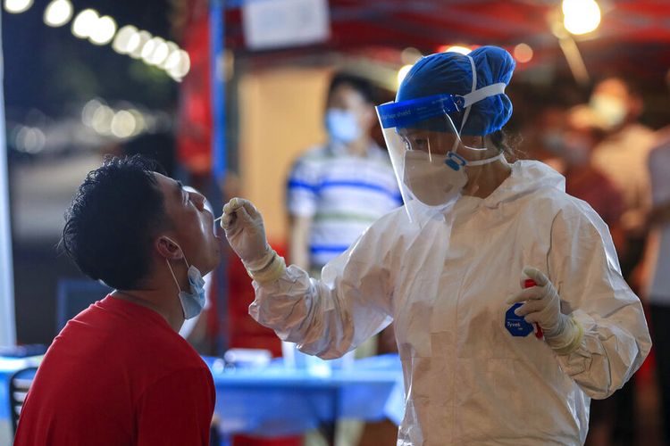 Seorang pekerja medis mengambil sampel swab dari seorang penduduk selama putaran tes Covid-19 massal di Wuhan di provinsi Hubei, China tengah, pada 5 Agustus 2021. 
