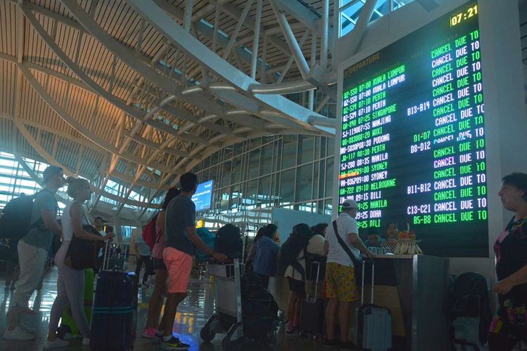 Sejumlah penumpang mencari informasi jadwal penerbangan melalui layar monitor di Bandara Ngurah Rai, Bali, Jumat (29/6/2018). PT Angkasa Pura I menutup sementara operasional Bandara Internasional I Gusti Ngurah Rai selama 16 jam mulai pukul 03.00 WITA hingga 19.00 WITA setelah Direktorat Jenderal Perhubungan Udara mengeluarkan NOTAM A2551/18 pada Jumat ini akibat dampak sebaran abu vulkanik Gunung Agung.