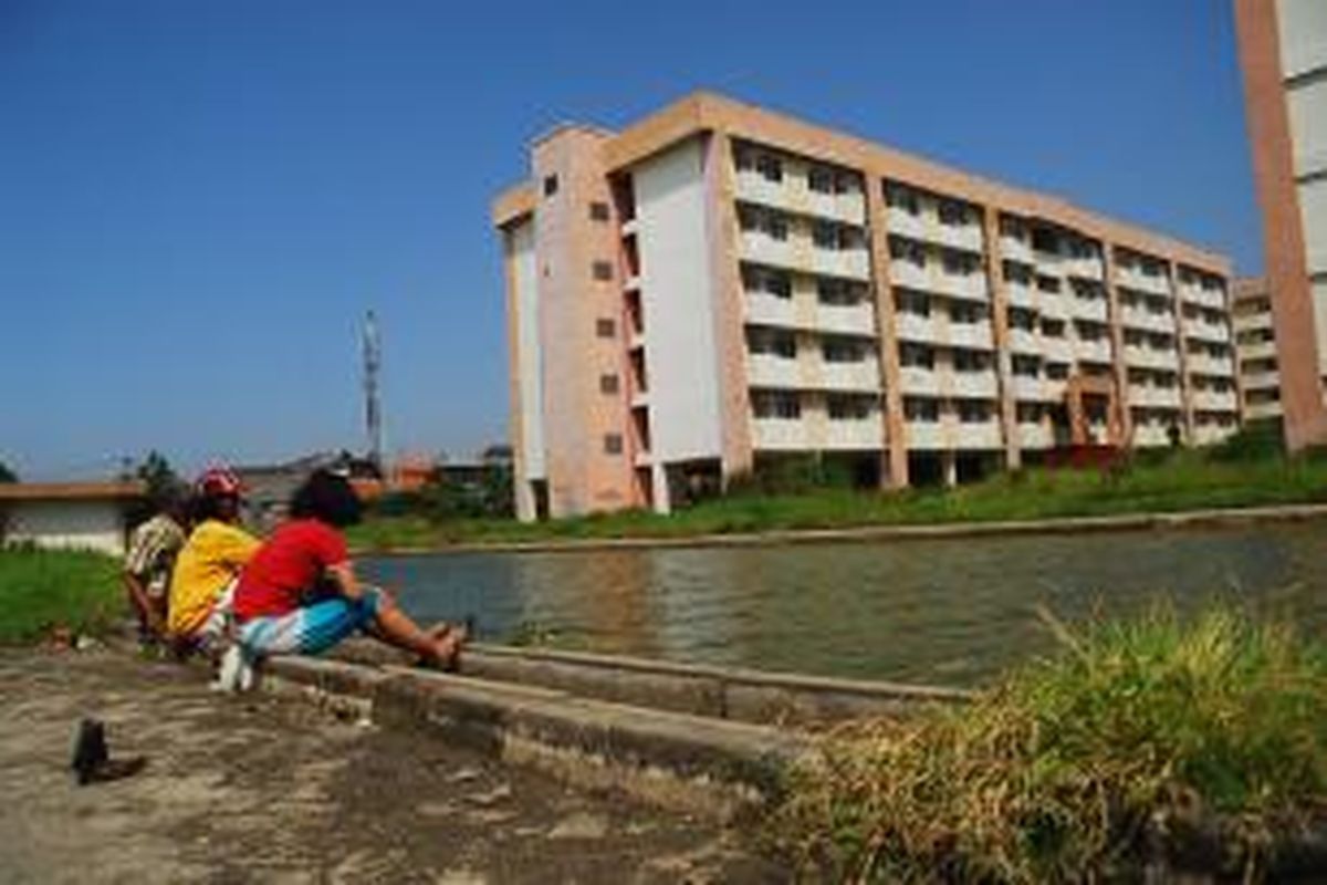 Warga Pisangan, Cakung, menghabiskan waktu senggang di tempat penampungan air di Rusun Jalan Komarudin, Cakung, Jakarta Timur, Kamis (21/8/2013). Kondisi tata air di komplek ini kurang bagus, dan sering meluap.
