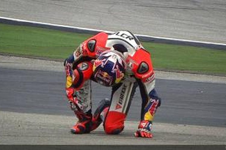 Pebalap LCR Honda asal Jerman, Stefan Bradl, memegangi ankle kanannya setelah mengalami kecelakaan saat sesi latihan empat GP Malaysia, yang berlangsung di Sirkuit Sepang, Sabtu (12/10/2013).