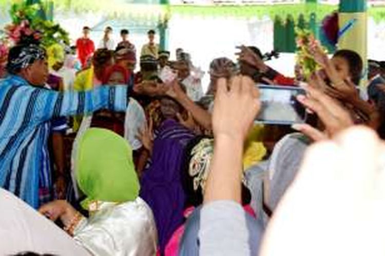 Bupati Buton, Umar Samiun (Mengenakan Jubah Adat Buton) menghamburkan uang pecahan Rp 100 ribuan kearah warga yang sedang menonton pesta adat wabula, Kecamatan Wabula, Sulawesi Tenggara, Rabu (20/7/2016).