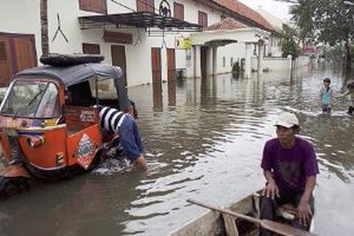 Tukang perahu menunggu warga yang menyeberang di Jalan Kakap, Jakarta Utara, Senin (21/1/2015). Banjir sudah lima hari menggenangi kawasan ini.