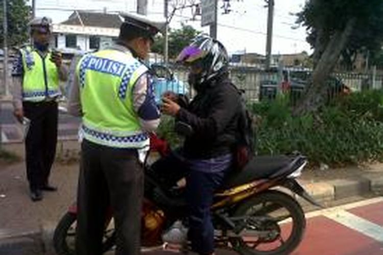 Polisi menilang para pengendara motor dalam operasi sterilisasi di jalur khusus bus transjakarta di koridor busway Pulogebang-Kampung Melayu, Jalan Raya Bekasi Timur, Jatinegara, Jakarta , Senin (25/11/2013).