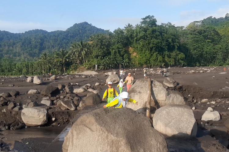 Anak-anak diantar orang tuanya berangkat sekolah di dusun sebrang sungai meski dusunnya terisolasi akibat erupsi Semeru