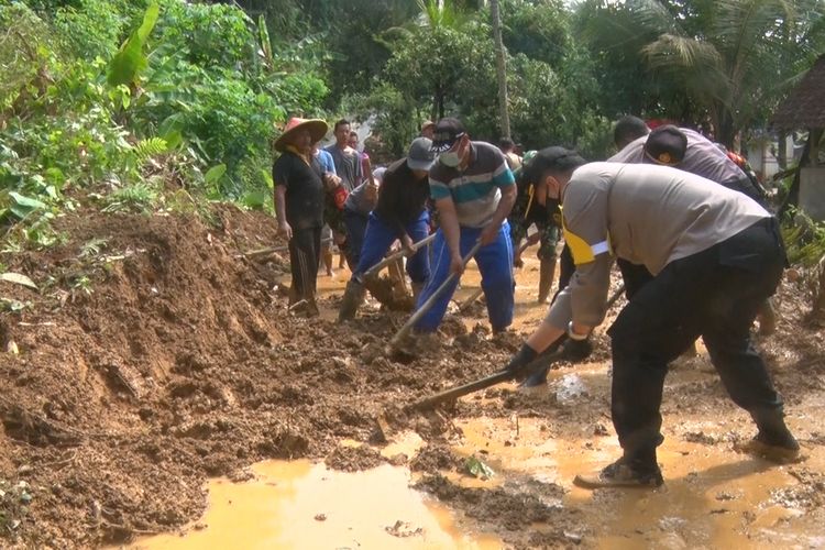 Sejumlah warga bersama TNI Polri, membersihkan material longsor yang menutup jalur penghubung antara kecamatan Munjungan-Kecamatan Watulimo Trenggalek Jawa Timur,Senin (26/10/2020).