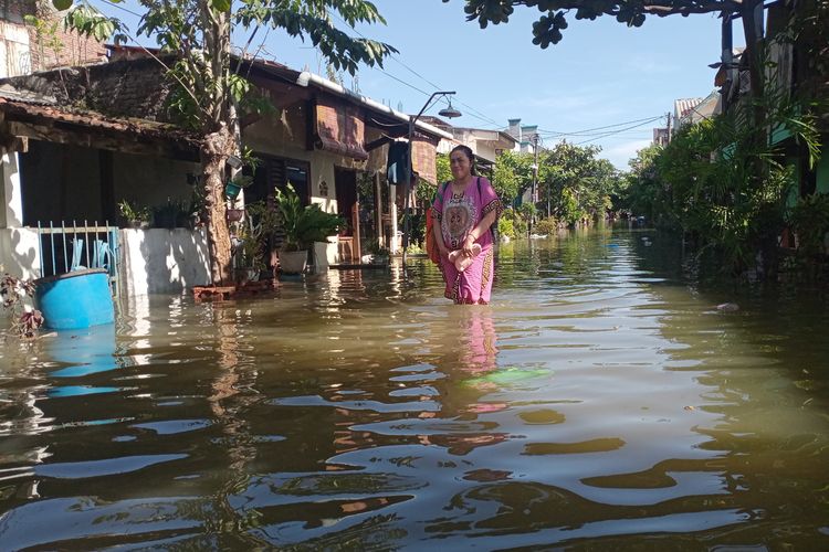 Warga nekat melintasi genangan rob yang melanda Desa Sriwulan Kecamatan Sayung Kabupaten Demak Jawa Tengah, Selasa (24/5/2022).