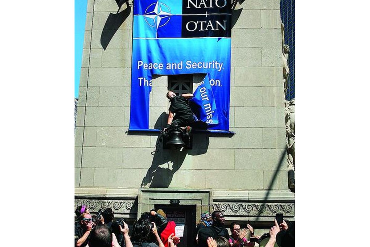Konferensi Tingkat Tinggi Pakta Pertahanan Atlantik Utara (NATO) di Chicago, AS, pekan ini diwarnai aksi demonstrasi, Jumat (18/5), saat seorang demonstran merobek spanduk NATO yang terpasang di jembatan Michigan Avenue, Chicago.