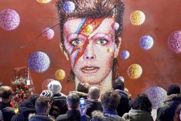 Massa berkumpul dan menempatkan bunga di bawah mural dari mendiang artis musik Inggris David Bowie, yang dilukis oleh seniman jalanan Australia James Cochran, di Brixton, London Selatan, 11 Januari 2016 waktu setempat. Bowie meninggal dunia di New York, AS, pada Minggu, 10 Januari 2016 waktu setempat, dalam usia 69 tahun akibat kanker.