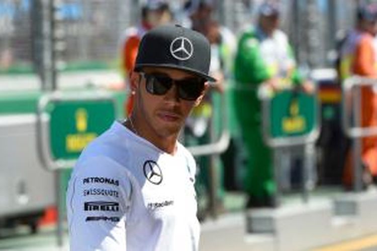 Pebalap Mercedes asal Inggris Lewis Hamilton berjalan di area pit Sirkuit Albert Park, Melbourne, pada sesi latihan GP Australia, Jumat (14/3/2014).