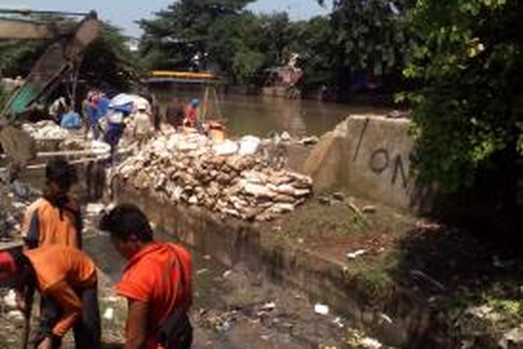 Sejumlah pekerja memperbaiki tanggul jebol di Kali Sunter, tepatnya di dekat jembatan Mal Artha Gading, Kelapa Gading, Jakarta Utara, Sabtu (24/1/2015).