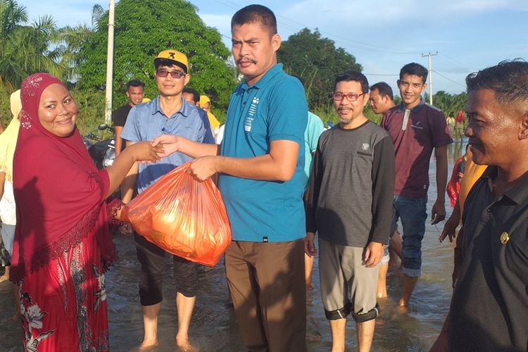 Kepala Desa Sontang Zulfahrianto menyerahkan bantuan kepada warganya yang terdampak banjir di Desa Sontang, Kecamatan Bonai Darussalam, Kabupaten Rohul, Riau, Sabtu (30/11/2019).