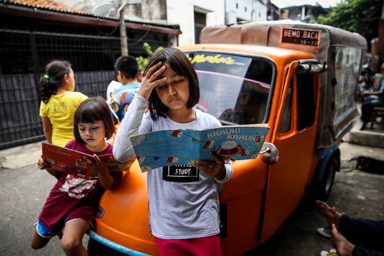 Anak-anak membaca buku di bemo perpustakaan di Jalan Karet Pasar Baru Barat II, Tanah Abang, Jalarta Pusat, Jumat (7/12/2018). Pak Sutino (58) adalah sopir bemo yang merintis bemo tuanya menjadi perpustakaan keliling bagi anak-anak sejak tahun 2013.  Pak Sutino (58) adalah sopir bemo yang merintis bemo tuanya menjadi perpustakaan keliling bagi anak-anak sejak tahun 2013.