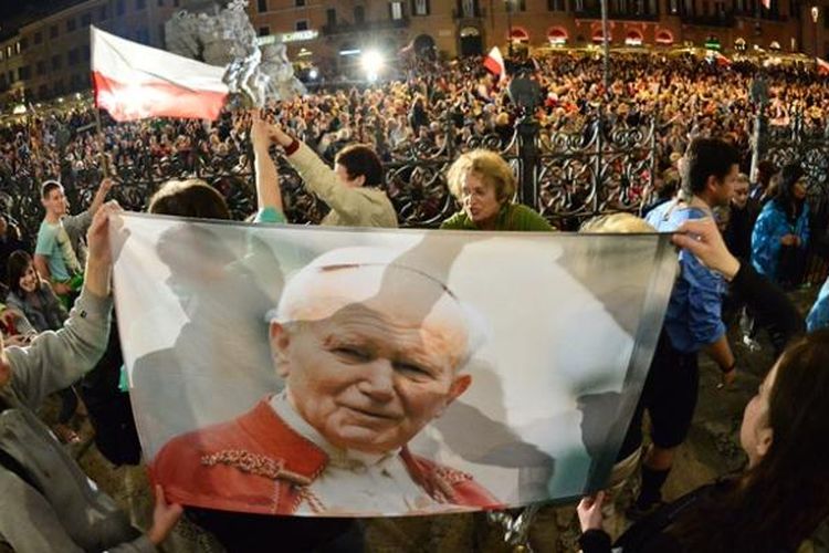 Sejumlah peziarah Katolik memegang foto mendiang Paus Yohanes Paulus II yang meninggal dunia sembilan tahun lalu di jalanan kota Roma tak jauh dari Vatikan. Paus Fransiskus dijadwalkan memimpin upacara kanonisasi Paus Yohanes XXIII dan Paus Yohanes Paulus II pada Minggu (27/4/2014).
