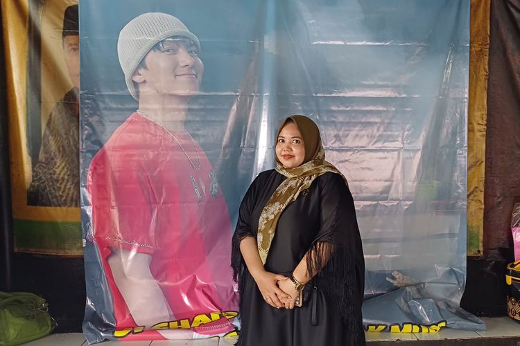 Ocha, istri pemilik Warung Sate Pak Muri RSPP yang didatangi aktor Korea Selatan, Ji Chang Wook berfoto di depan banner yang dipasang di warungnya, di Kebayoran Lama, Jakarta Selatan, Senin (13/5/2024).