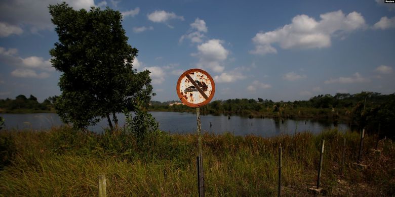 Tanda Dilarang Berenang tampak di bekas lubang tambang batu bara yang terisi air di Kabupaten Kutai Kertanegara, Kalimantan Timur, 30 Agustus 2019.