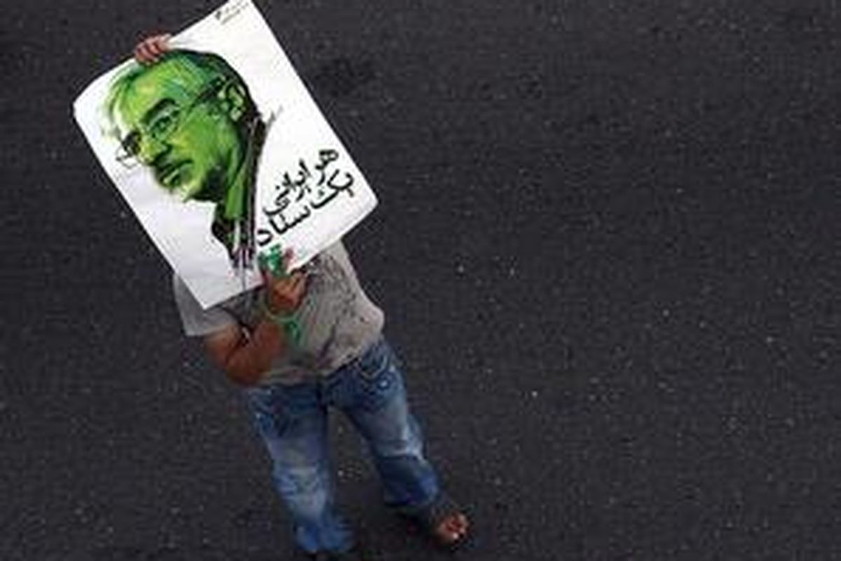 Seorang demonstran memegang poster Mir Hossein Mousavi.