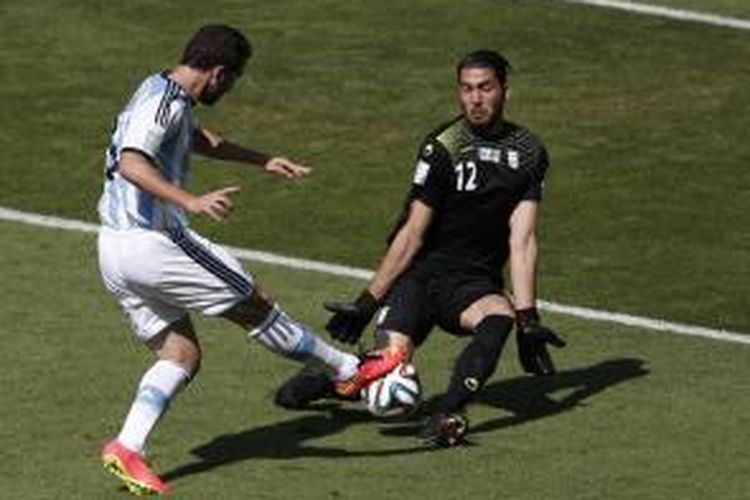Striker Argentina, Gonzalo Higuain (kiri), gagal mencetak gol karena bola tendangannya bisa ditahan kiper Iran, Alireza Haghighi, pada matchday kedua penyisihan Grup F Piala Dunia 2014, Sabtu (21/6/2014).