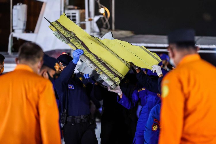 Indonesian National Police Disaster Victim Identification (DVI) personnel haul a body bag containing the remains of a victim of Sriwijaya Air Flight SJ 182 on Friday (15/1/2021)