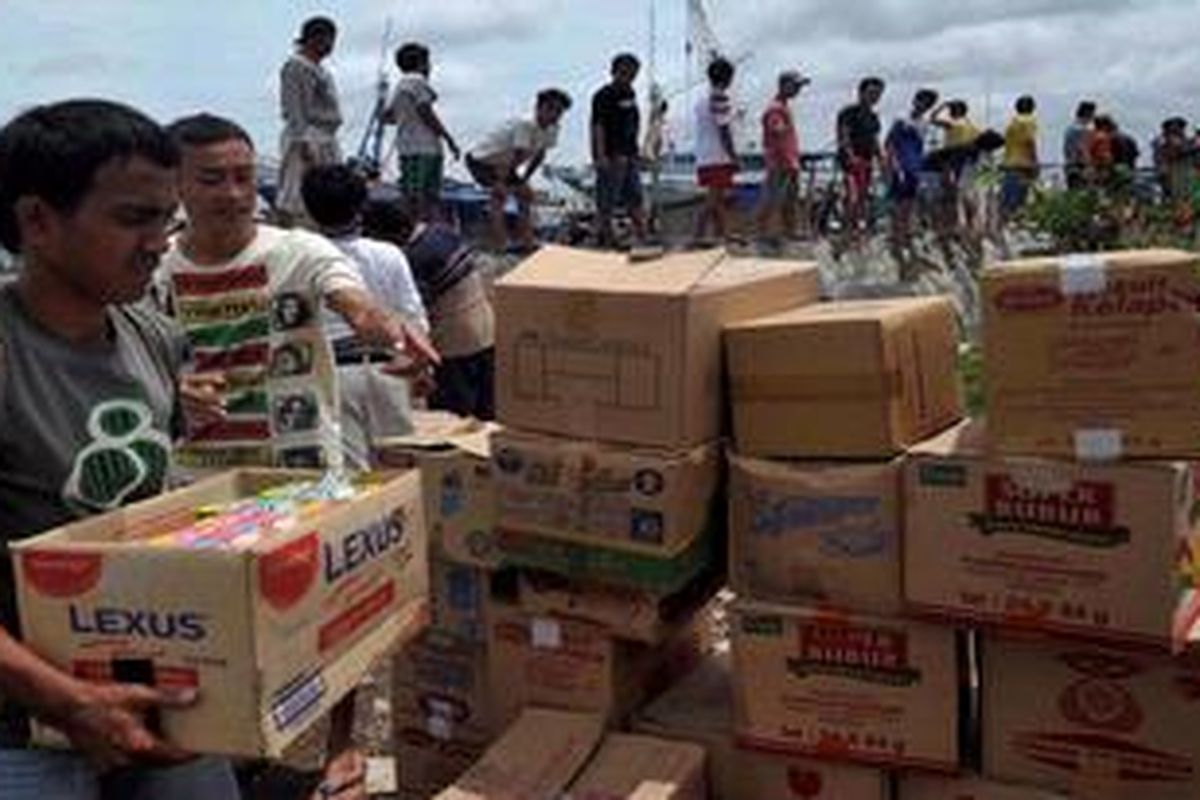 Warga korban banjir bergotong royong menurunkan bantuan sumbangan donatur yang didistribukan melalui jalur laut di Kampung Muara Baru, Penjaringan, Jakarta Utara, Kamis (24/1/2013). Penyaluran lewat laut dilakukan karena jalur darat sebagian masih tergenang dan macet.