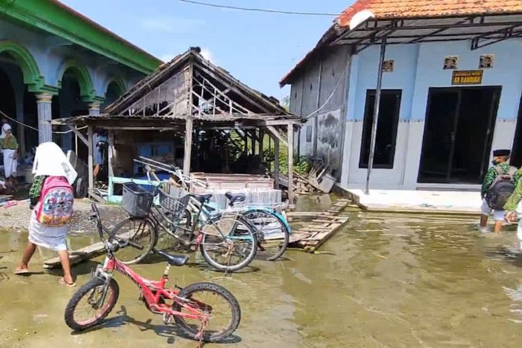 Siswa MI Roudhotul Ulum yang berada di Desa Sumowinangun, Kecamatan Karangbinangun, Lamongan, semangat mengikuti PTM meski sementara dilaksanakan di masjid dan musala desa setempat lantaran gedung sekolah kebanjiran.