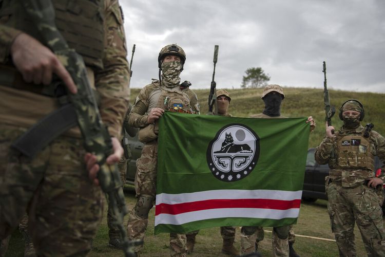 Relawan tentara berpose dengan bendera Republik Chechnya Ichkeria setelah pelatihan di luar Kyiv, Ukraina, Sabtu, 27 Agustus 2022. 