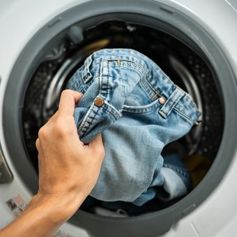 Ilustrasi mencuci celana jeans di mesin cuci. 