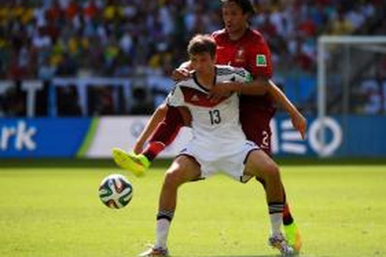 Striker Jerman, Thomas Mueller, saat berebut bola dengan bek Portugal, Bruno Alves, pada pertandingan Grup G Piala Dunia 2014 di Arena Fonte Nova, Salvador, Senin (16/6/2014)