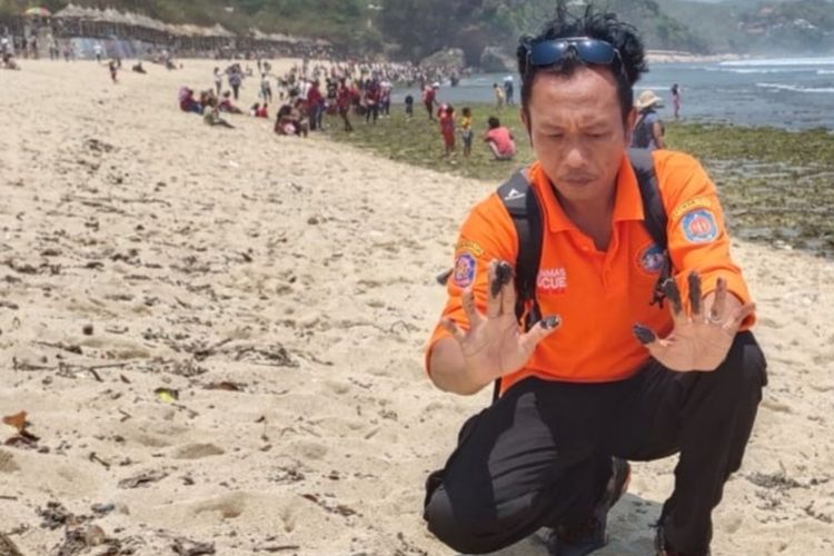 Sekretaris Satlinmas Rescue Istimewa Wilayah Operasi II Pantai Baron Surisdiyanto menunjukkan limbah mirip solar saat dipegang di Pantai Krakal, Gunungkidul
