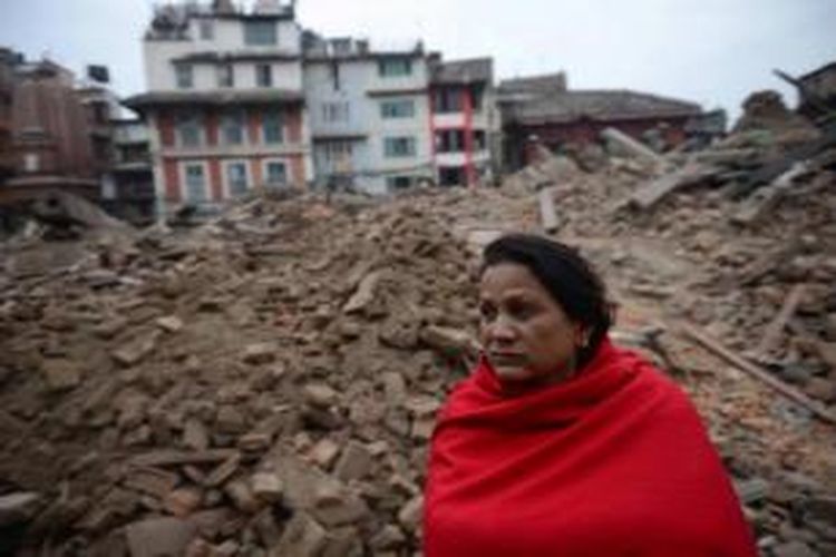 Seorang warga duduk di dekat reruntuhan bangunan setelah gempa mengamuk di Kathmandu, 26 April 2015. Gempa tektonik berkekuatan 7.9 SR mengguncang Nepal pada 25 April, mengakibatkan ribuan orang meninggal.