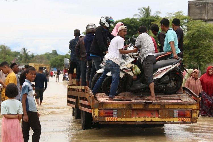 Warga menaiki truk untuk bisa melewati banjir di Desa Parang Sikureung, Kecamatan Matangkuli, Aceh Utara, Kamis (6/10/2022)