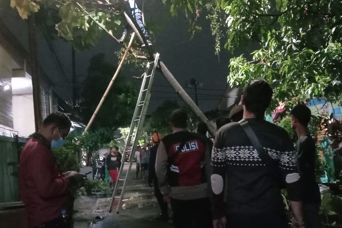 Petugas kepolisian dan petugas PLN saat memperbaiki pohon tumbang akibat diterpa angin puting beliung di wilayah Kebalen, Kabupaten Bekasi. Selain pohon tumbang, beberapa atap rumah warga juga rusak akibat kencangnya angin.