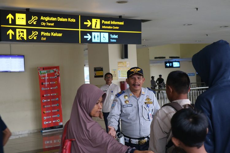 Petugas terminal Pulo Gebang tengah mencoba membantu penumpang yang baru turun dari bus dan menanyakan halte bus Transjakarta.