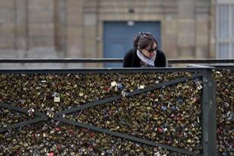 Seorang perempuan memperhatikan ribuan gembok cinta yang dipasang para turis di Jembatan Pont des Arts, Paris, Perancis. Pada Senin (1/6/2015), pemerintah kota Paris mulai melepas gembok-gembok cinta yang jumlahnya diperkirakan mencapai hampir 1 juta buah itu.