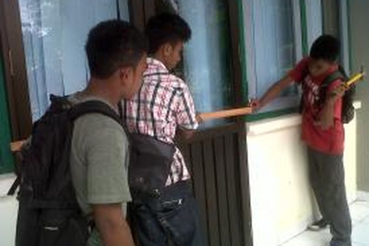 Mahasiswa Fakultas Ekonomi Unpati berunjuk rasa di depan kampus ekonomi,Selasa (21/1/2014). nampak tiga mahasiswa sedang menyegel salah satu pintu ruang kuliah dengan balok kayu 