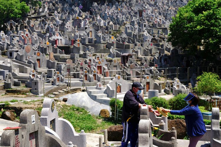 Sepasang suami istri membakar uang kertas di makam seorang kerabat di pemakaman selama Chinese Ching Ming, atau Hari Pembersihan Makam, di Hong Kong Selasa, 5 April 2022. 