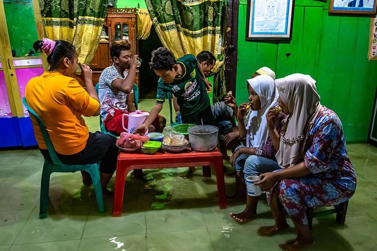 Warga berbuka puasa di dalam rumahnya yang terendam air rob (limpasan air laut ke daratan) di pesisir Sayung, Demak, Jawa Tengah, Selasa (12/5/2020). Sejak awal bulan Ramadhan, sejumlah desa di pesisir pantai utara Demak dilanda banjir rob setinggi sekitar 15-60 sentimeter pada sore hingga malam hari yang memaksa warga setempat menjalankan sejumlah aktivitas ibadah Ramadhan seperti berbuka puasa dalam keadaan terendam rob.