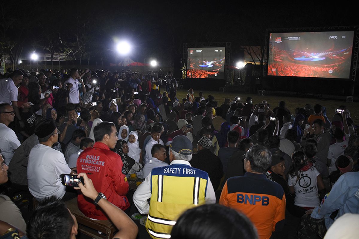 Presiden Joko Widodo (ketiga kiri) didampingi Gubernur NTB TGB Zainul Majdi (kedua kiri) bersama warga korban gempa nonton bareng upacara penutupan Asian Games 2018 di Lapangan Kecamatan Gunungsari, Lombok Barat, NTB, Minggu (2/9/2018). Presiden Jokowi di sela kunjungannya ke lokasi gempa menyempatkan diri untuk nonton bareng warga korban gempa upacara penutupan Asian Games 2018.