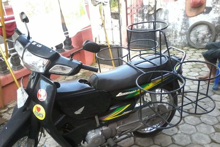 Sepeda motor yang dilengkapi perlengkapan keranjang untuk angkut galon air atau tabung gas.