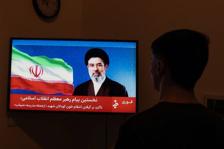 Seorang pria menyaksikan tayangan televisi yang menampilkan pidato pertama Mojtaba Khamenei sebagai Pemimpin Tertinggi Iran pada Kamis (12/3/2026).