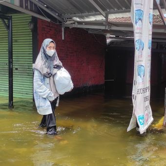 Salah satu warga melintasi genangan banjir di Kelurahan Bintoro, Kecamatan Demak, Kabupaten Demak, Selasa (19/3/2024). (KOMPAS.COM/NUR ZAIDI)