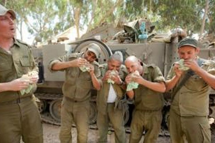 Sekelompok prajurit Israel sedang menyantap makanan di sela-sela tugas mereka di perbatasan negeri itu dengan Jalur Gaza.