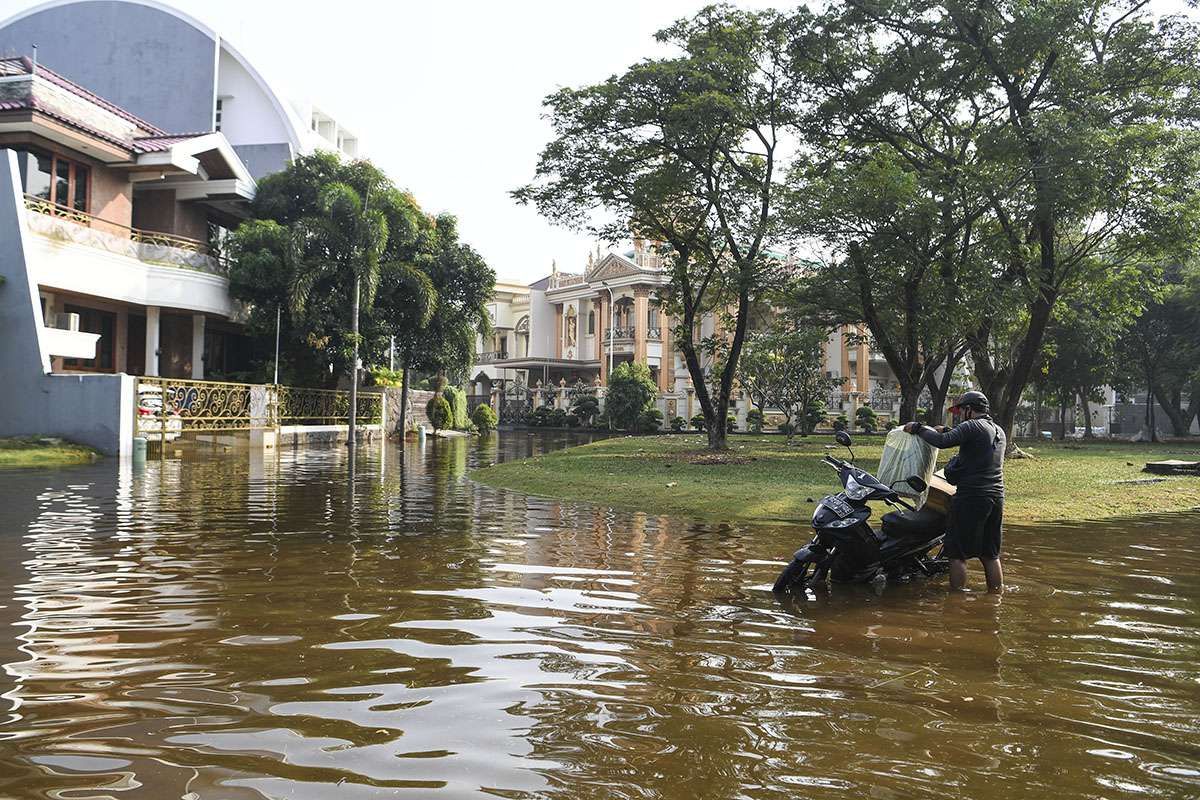 Pengendara motor menata barang bawaannya di atas motor yang mogok akibat banjir rob di Kompleks Pantai Mutiara, Penjaringan, Jakarta, Minggu (7/6/2020). Banjir di kawasan tersebut diduga akibat adanya tanggul yang jebol saat naiknya permukaan air laut di pesisir utara Jakarta.