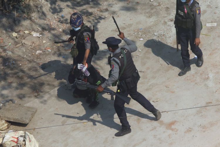 Polisi anti huru-hara memegangi seorang pengunjuk rasa sementara yang lainnya bersiap memukuli dalam insiden di Tharkata, luar Yangon, Myanmar,pada 6 Maret 2021.