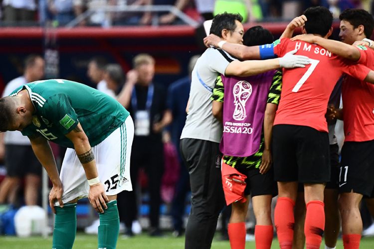 Pemain Jerman Niklas Suele (kiri) bereaksi dengan latar belakang pemain Korea Selatan yang sedang merayakan kemenangan dalam laga penyisihan Grup F Piala Dunia 2018 di Kazan Arena, Kazan, Rabu (27/6/2018). Sang juara bertahan Jerman terdepak dari ajang Piala Dunia usai ditaklukkan Korea Selatan dengan skor 2-0.